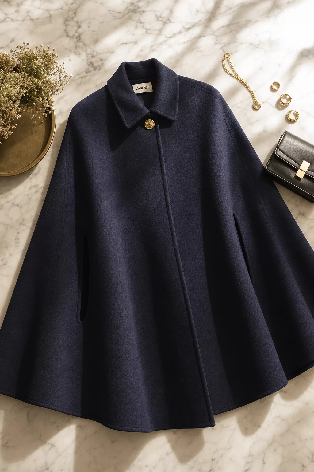 a beautiful editorial flat-lay of an elegant dark navy wool cape coat draped