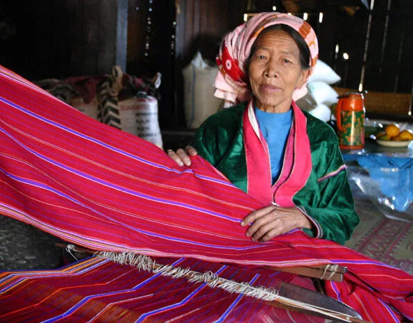 زنی از قوم پالاونگ (Palaung) در حال بافتن پارچه‌ای رنگارنگ روی دار قالی زانویی.